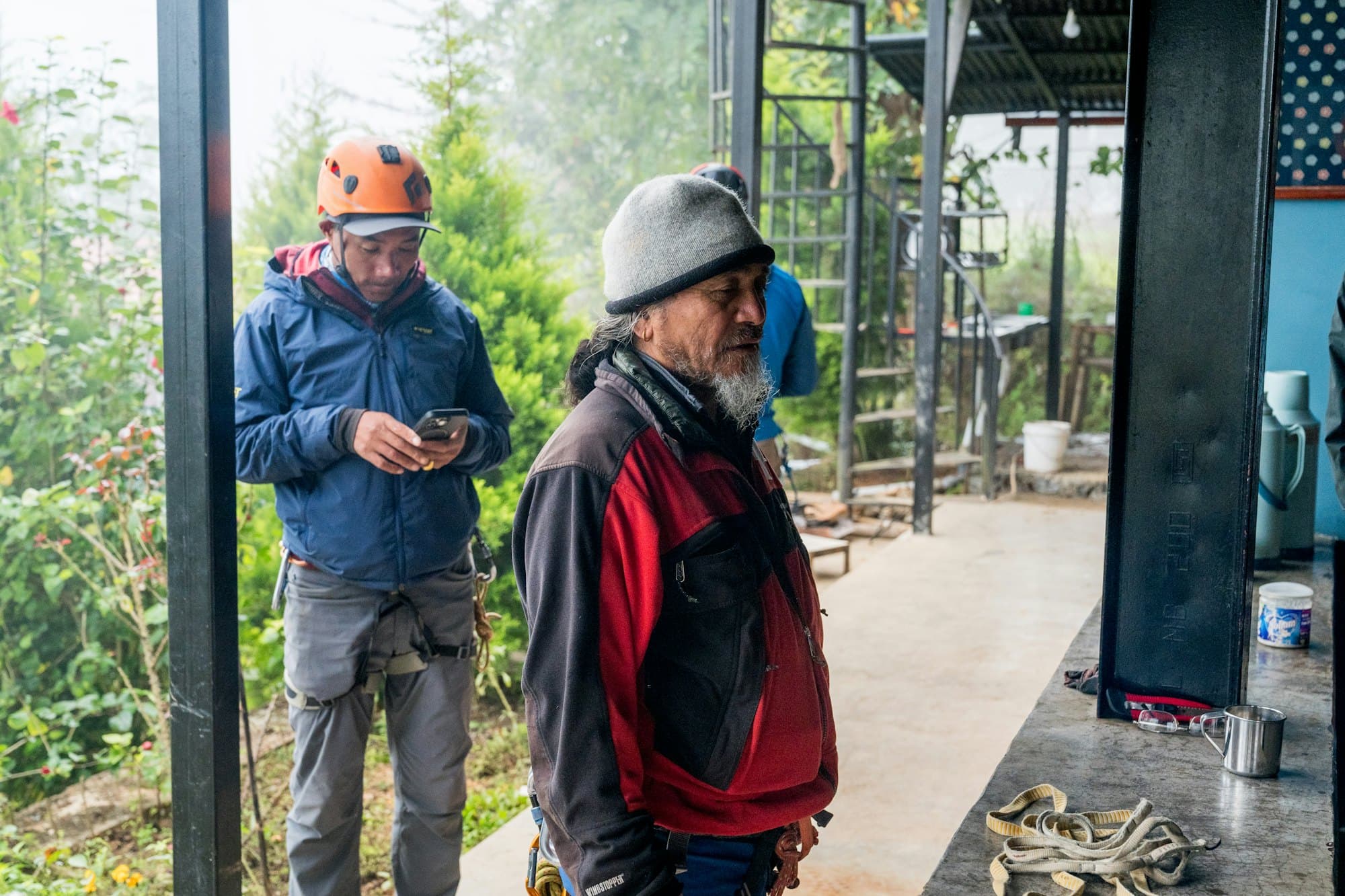 Two workers on a site, one checking his phone while the other talks