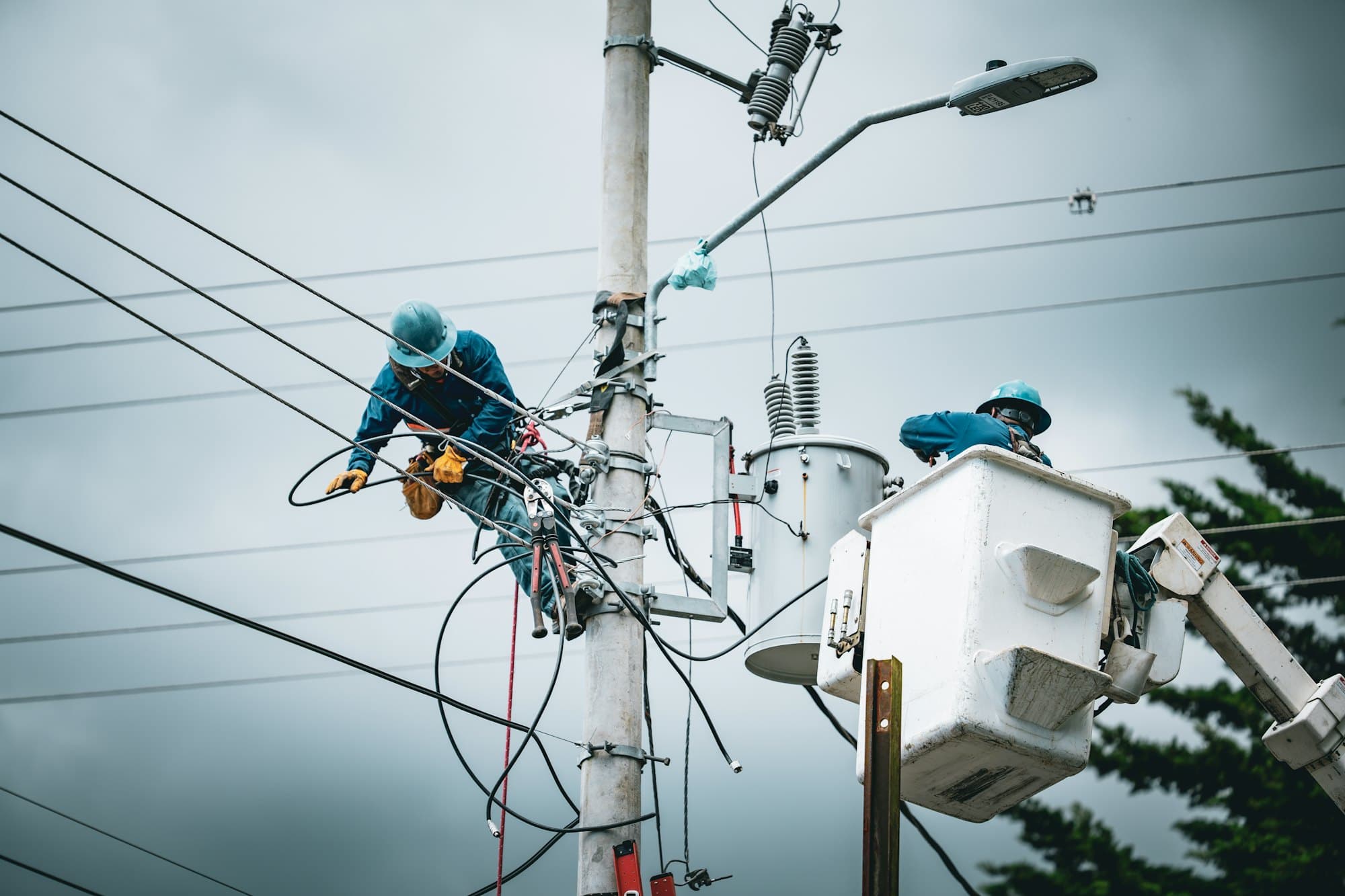 Linemen working on a utility pole and in a bucket truck